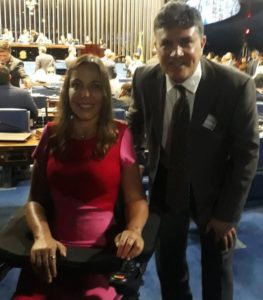 Ao fundo, Senado Federal. Em destaque, olhando para a frente e sorrindo, senadora Mara Gabrilli na cadeira de rodas ao lado de José Muniz, em encontro para debater o tema da pessoa com deficiência.